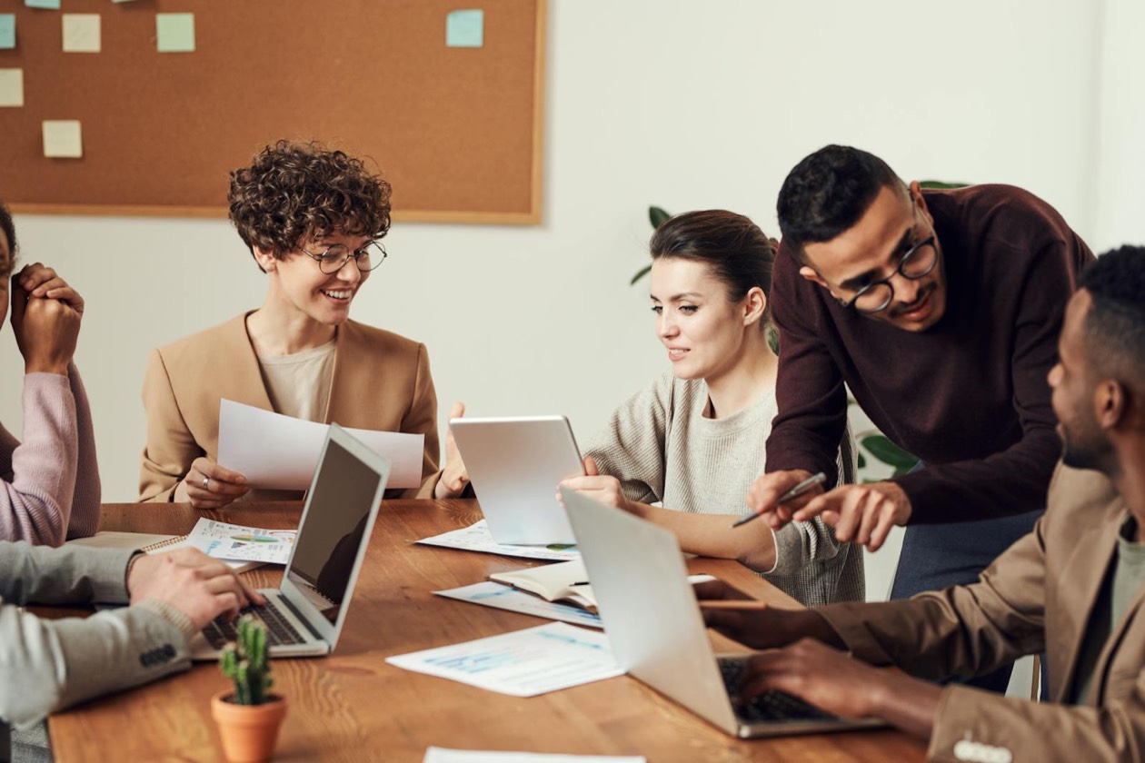 Team di marketing in riunione attorno a un tavolo con laptop e appunti &mdash; sessione strategica evidence-based