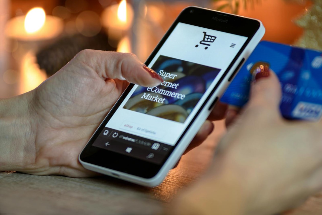 Persona con smartphone e carta di pagamento &mdash; touchpoint continui e mental availability per il consumatore occasionale