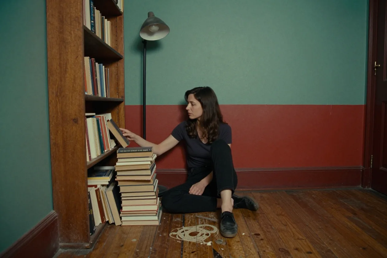 Una mujer sentada en el suelo devuelve un libro a un estante bajo