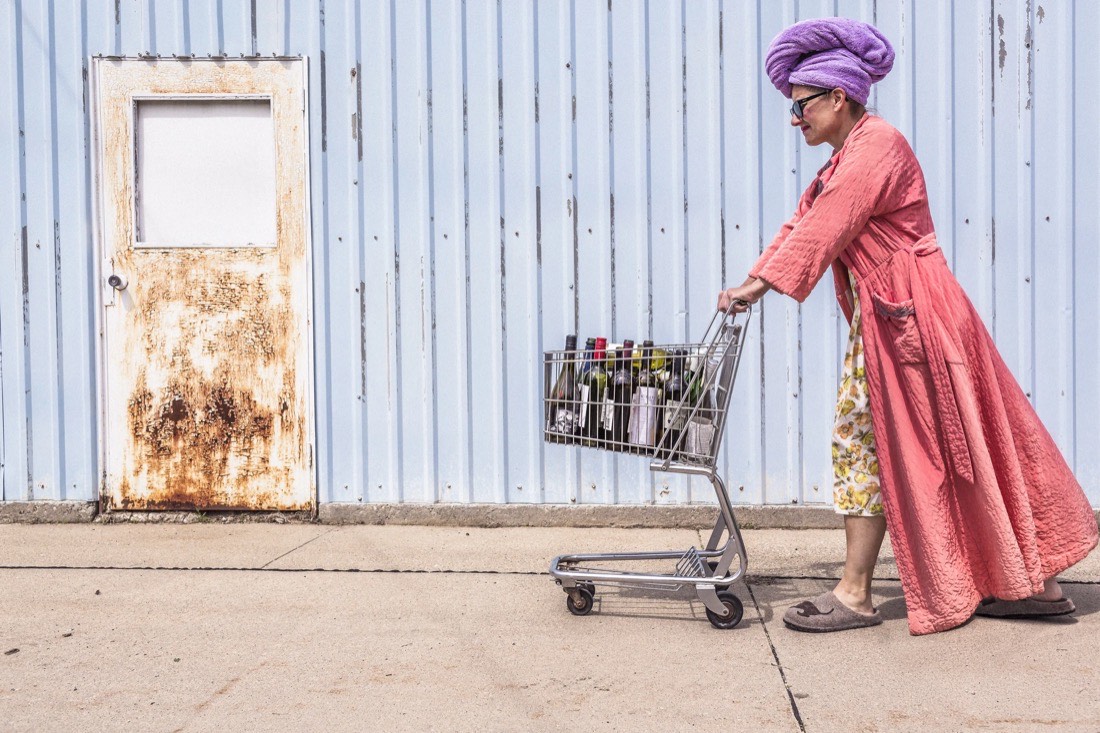 Woman in a pink robe pushing a shopping trolley along a blue wall
